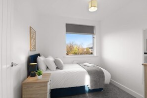 A bedroom with a bed, bedside table, lamp, window, and a view of the outside. - Perfect Booking 5 min Drive to Blyth Beach (Blyth)