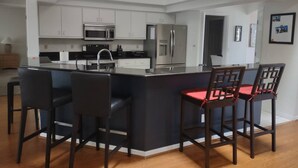 Une cuisine moderne dotée d’un îlot central, de tabourets de bar et d’une table à manger.