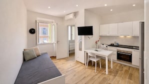 En kompakt bolig med tekøkken, spiseplads og sofa.