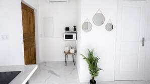 A modern kitchen with white cabinets, a microwave, a coffee maker, and a potted plant. - Bright Studio Flat in Cap d Ail - Near Monaco (Cap d'Ail)