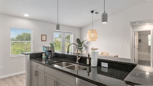A modern kitchen with a granite countertop, stainless steel sink, and pendant lighting. - Villa Verde Cozy Home In New Community (Inverness)