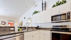 A modern kitchen with white cabinets, a built-in microwave, and a dishwasher. - Villa Havelaar Family Friendly and Awesome Pool (Inverness)