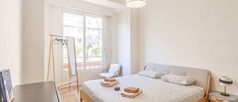 Un dormitorio con cama, mesita de noche, lámpara y ventana con vistas.