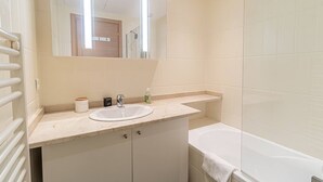 Un baño con lavamanos, espejo y bañera.