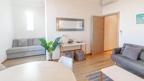 Una sala moderna con un sofá, una mesa de comedor, un escritorio pequeño y una planta en maceta.