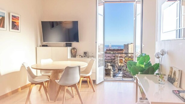 Una sala de estar moderna con comedor, un televisor de pantalla plana y un balcón con vista a la ciudad.