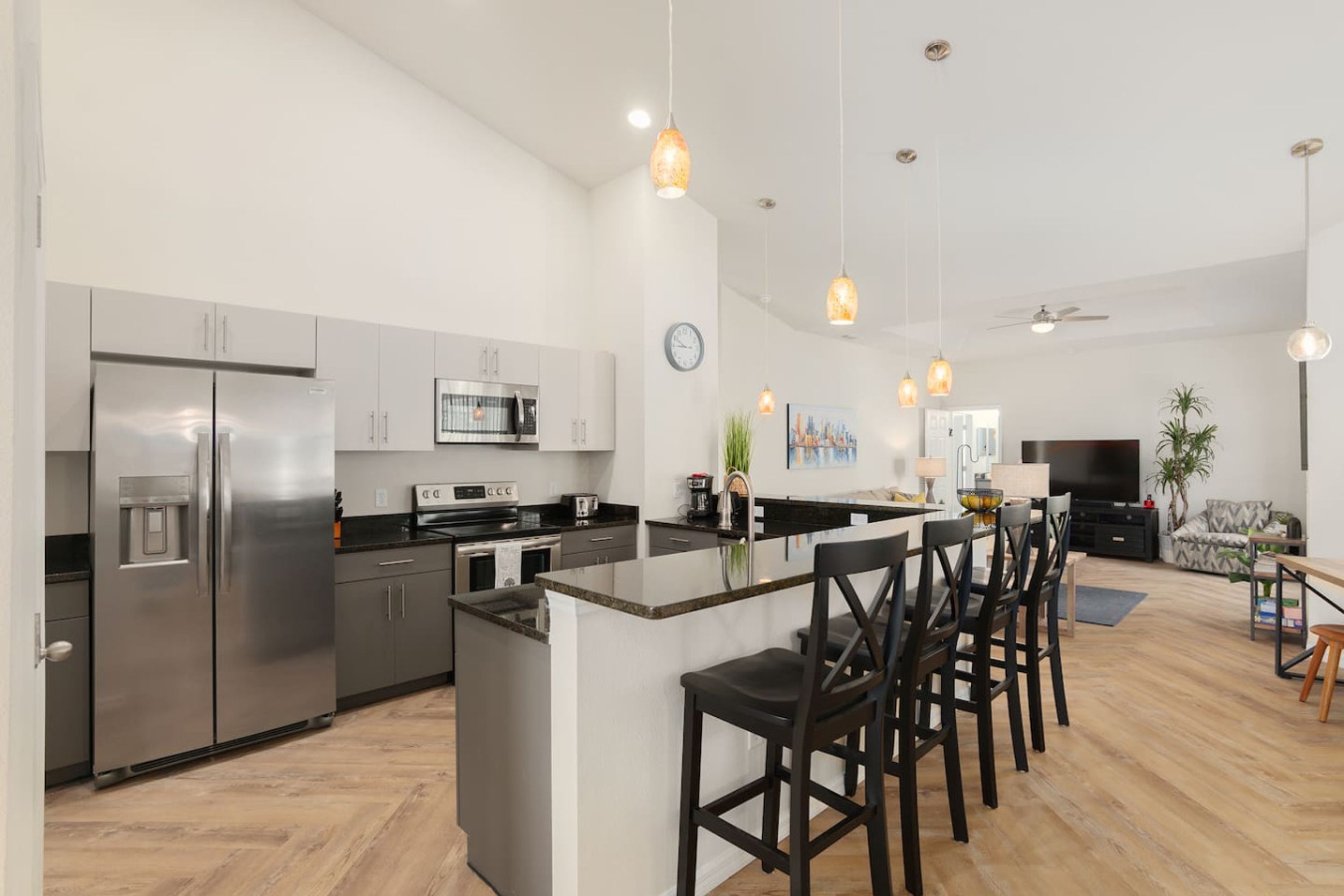 A modern kitchen with stainless steel appliances, a central island with bar stools, and pendant lighting.