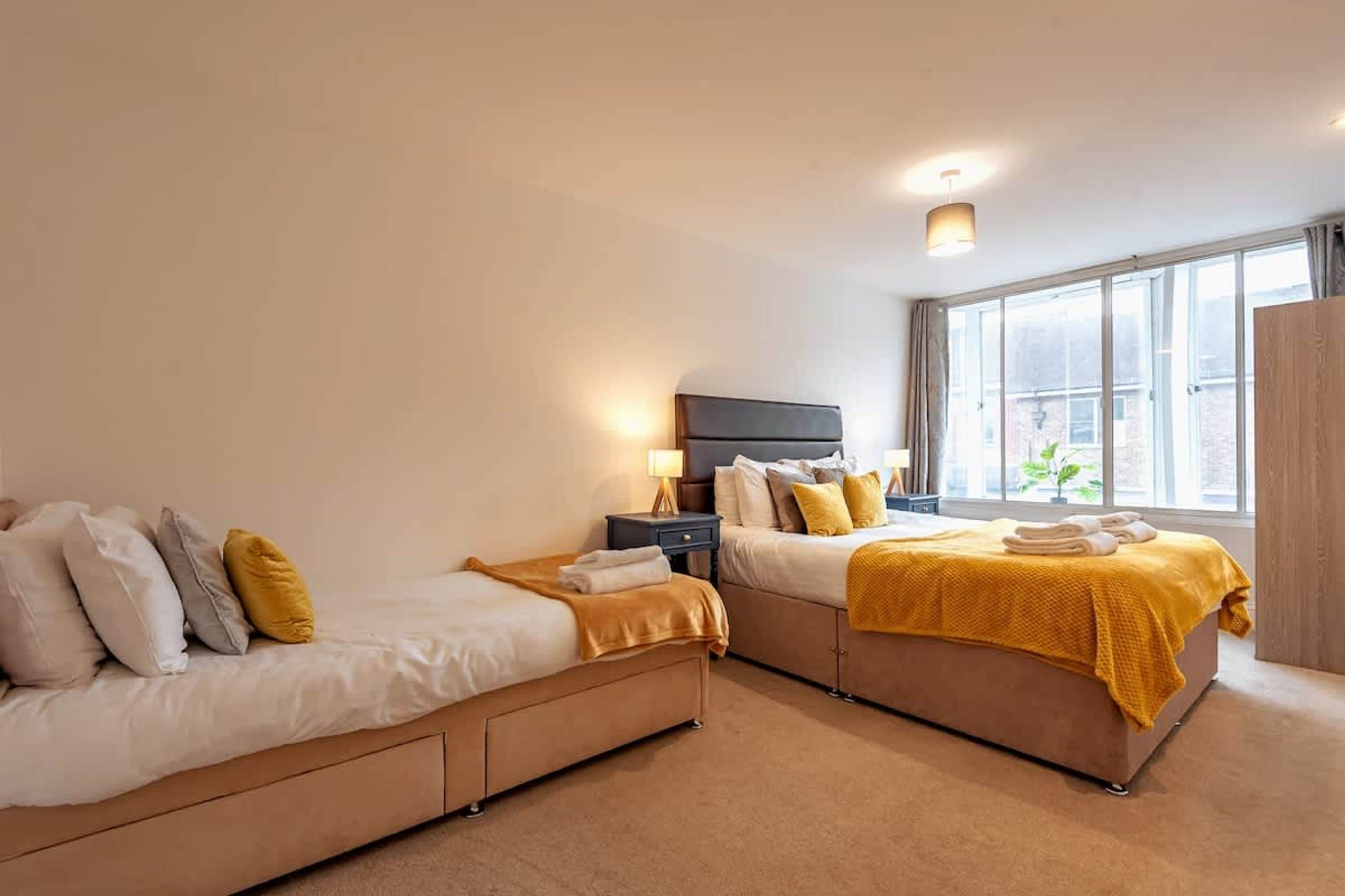 Une chambre avec deux lits, une table de chevet, une lampe et une fenêtre donnant sur un beau paysage.