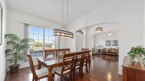 A spacious dining area with a large wooden table, multiple chairs, and a hanging light fixture. - Villa S G Spacious 5 Bedroom Family Vacation Home (Inverness)