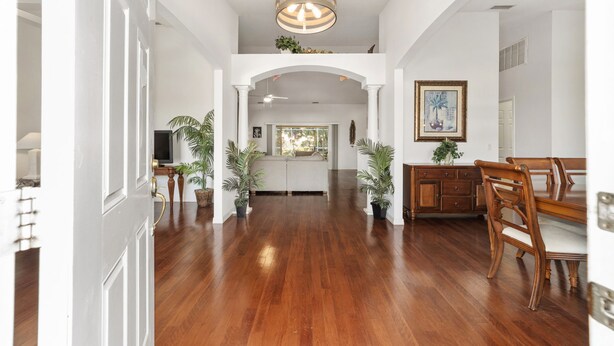A spacious interior with a wooden floor, white walls, and a dining area with wooden furniture. - Villa S G Spacious 5 Bedroom Family Vacation Home (Inverness)