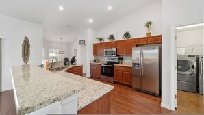 A modern kitchen with granite countertops, stainless steel appliances, wooden cabinets, and a built-in oven. - Villa S G Spacious 5 Bedroom Family Vacation Home (Inverness)