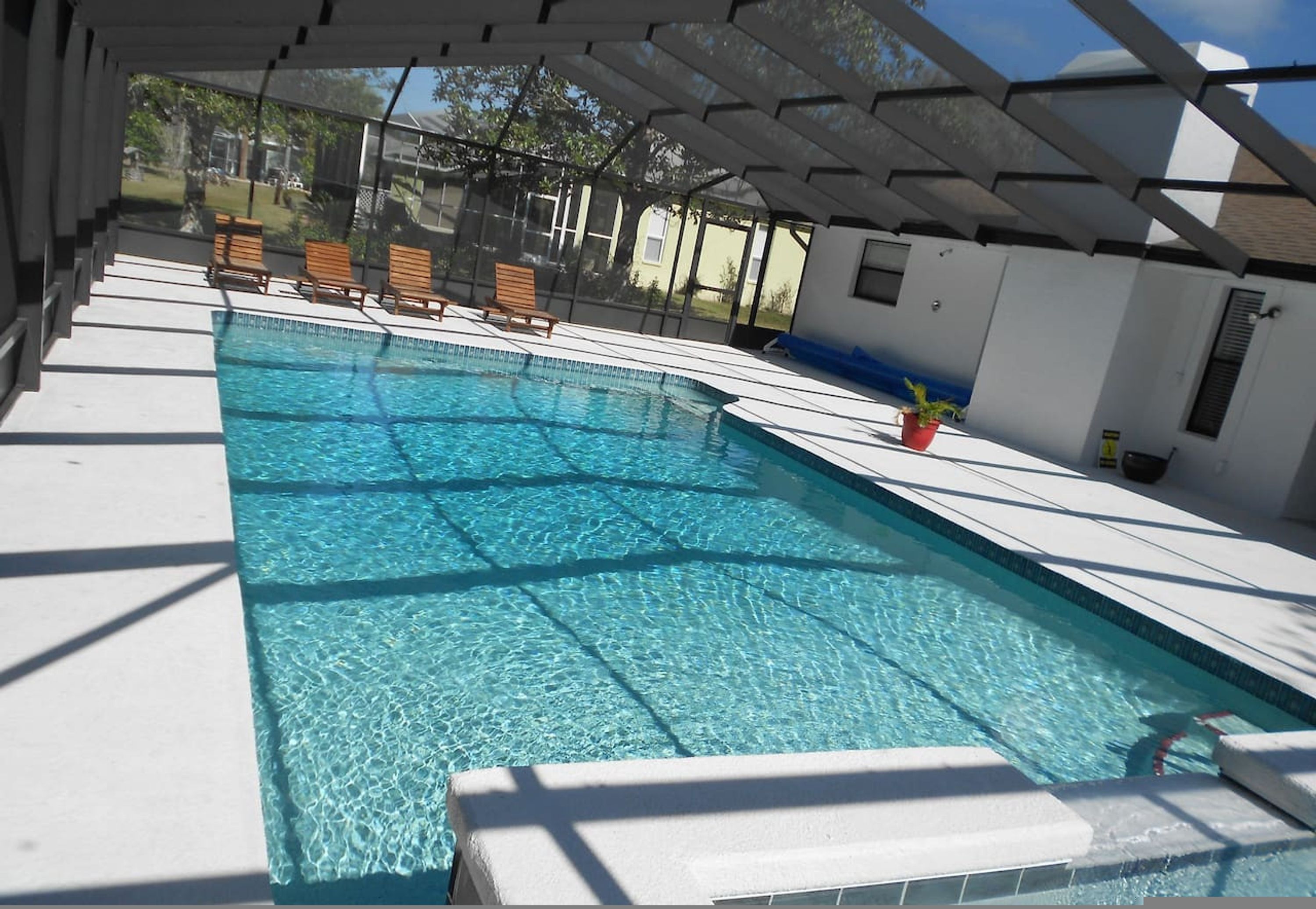 A clear swimming pool with lounge chairs and a covered area.