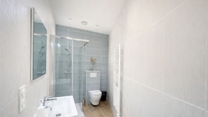 Un bagno moderno con cabina doccia in vetro, lavandino bianco e water.