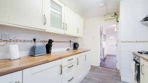 A kitchen with white cabinets, a wooden countertop, a toaster, a coffee maker, and a sink. - High Wycombe Home Free Parking Free Wifi Garden (High Wycombe)