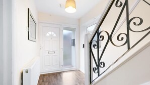 A hallway with a white door, a radiator, and a staircase with a black railing. - High Wycombe Home Free Parking Free Wifi Garden (High Wycombe)