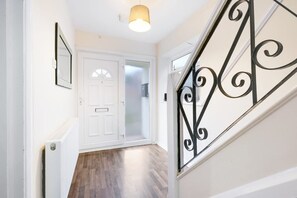 A hallway with a white door, a radiator, and a staircase with a black railing. - High Wycombe Home Free Parking Free Wifi Garden (High Wycombe)
