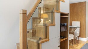 A modern staircase with glass railings, a desk with a chair, and a television. - Stylish 1-bed Flat in the Heart of Kensington (London)