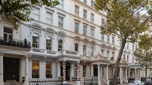 A row of classic, white, multi-story buildings with ornate architectural details, including columns and decorative moldings. - Stylish 1-bed Flat in the Heart of Kensington (London)