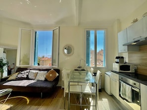 A compact living space with a sofa, dining table, and kitchen area. - Charming T2 - 2 Minutes Walk From Monaco (Beausoleil)