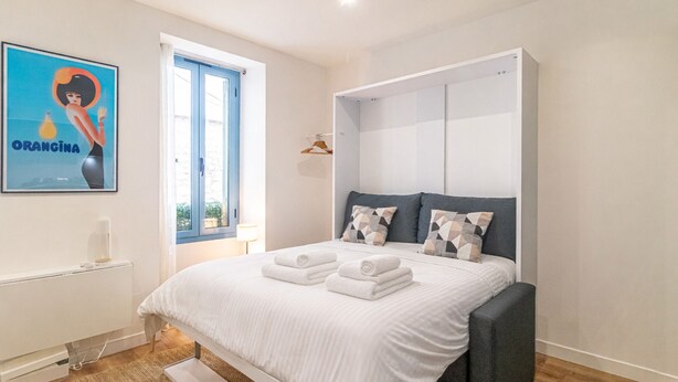 Ein Schlafzimmer mit Bett, Kleiderschrank, Heizkörper, einem Poster und einem Fenster.