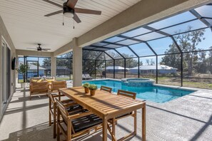 A covered patio with a pool, wooden furniture, and a ceiling fan. - Villa Bennett NEW 4-bedroom With Pool spa (Inverness)