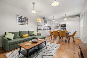 Ein modernes Wohnzimmer mit einem grünen Sofa, einem Holztisch und einem Essbereich mit gelben Stühlen.