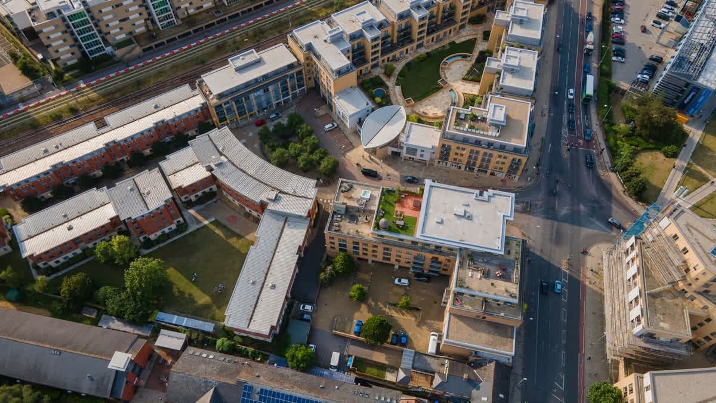 An aerial view of a multi-story building complex with a central courtyard, parking areas, and adjacent roads.