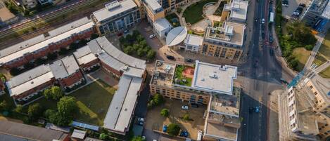 An aerial view of a multi-story building complex with a central courtyard, parking areas, and adjacent roads.