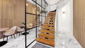 Un interno moderno con una scala in legno, pareti di vetro e un pavimento in marmo.