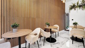 Arredamento moderno con listelli di legno, pavimento in marmo e tavoli rotondi con sedie.