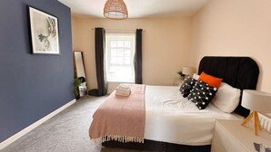 A bedroom with a bed, bedside table, lamp, and a hanging light fixture.