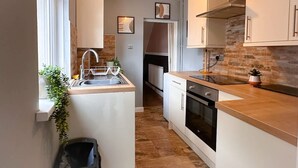 A compact kitchen with a sink, stove, and cabinets.