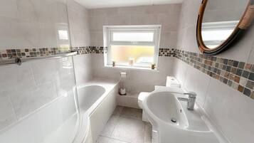 A modern bathroom with a bathtub, a sink, and a toilet. There is a window with a view of the outside.