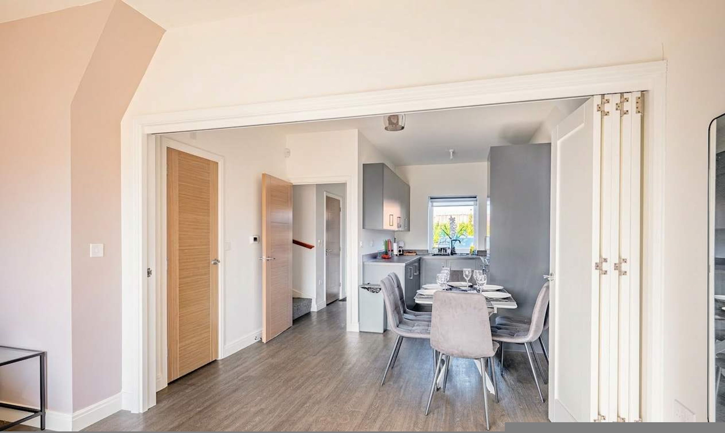 A modern interior with a dining area, kitchen, and a hallway leading to another room.