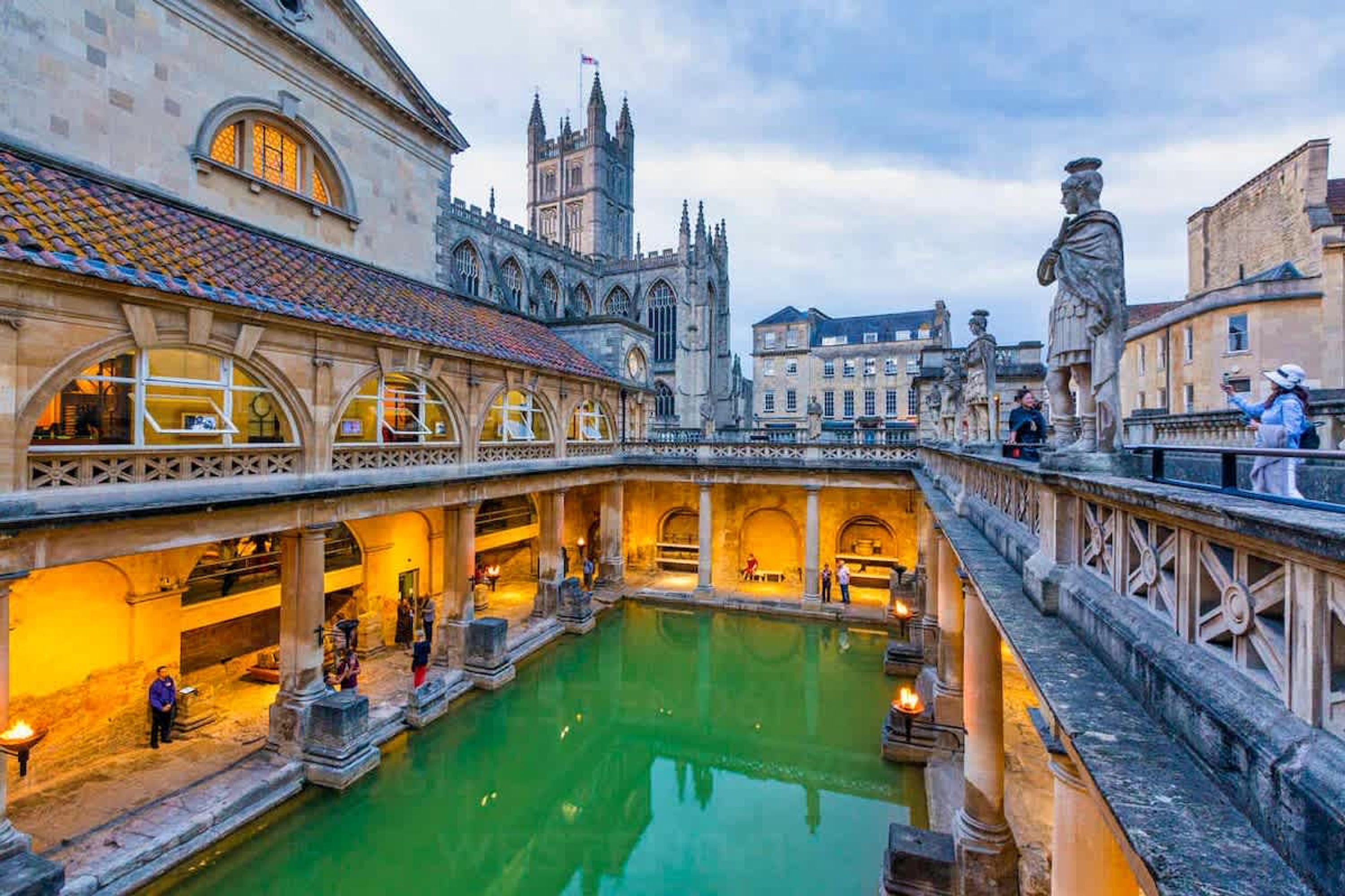 A historic building with a courtyard, stone statues, and a large water feature.