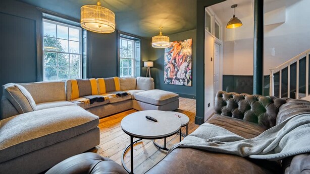 A living room with a sectional sofa, a round coffee table, and a tufted headboard. - Stunning Bath Home Sleeps 12 Ideal for Hen Stags (Bath)