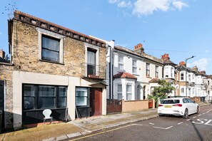 A row of terraced houses with a white car parked on the street. - Perfect Booking 3 Bed Home In Kensal Green (London)