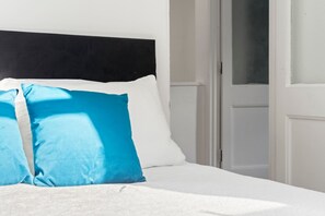 A bed with a black headboard, white bedding, and two pillows, one blue and one white. - Perfect Booking 3 Bed Home In Kensal Green (London)
