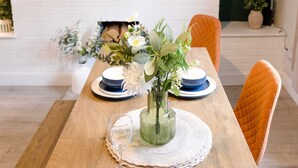 A dining table set with plates, a glass, and a vase with flowers. - Perfect Booking 4 Bed Home in Aberdare (Aberdare)