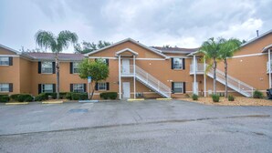 A multi-story hotel with a central staircase, balconies, and a parking lot. - Apartment Live Oak Landing (Inverness)