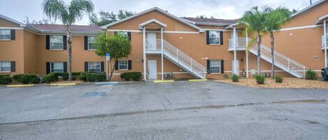 A multi-story hotel with a central staircase, balconies, and a parking lot.