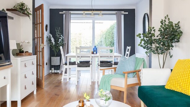 A living room with a dining table, a sofa, a coffee table, and a TV stand. - Perfect Booking 4 Bed Home Near City Airport (Cheadle)