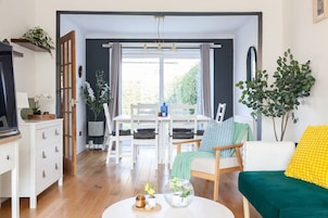 A living room with a dining table, a sofa, a coffee table, and a TV stand.
