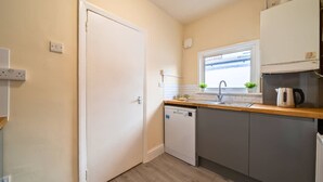 A compact kitchen with a dishwasher, a sink, and a window above it. - 2 Bedroom SE London Home - Cosy Great Location (London)