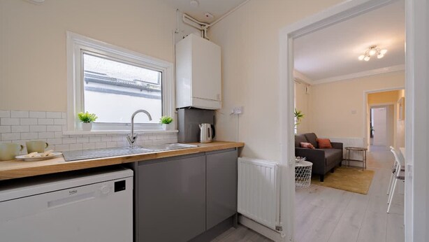 A compact kitchen with a dishwasher, a window, and a radiator. - 2 Bedroom SE London Home - Cosy Great Location (London)