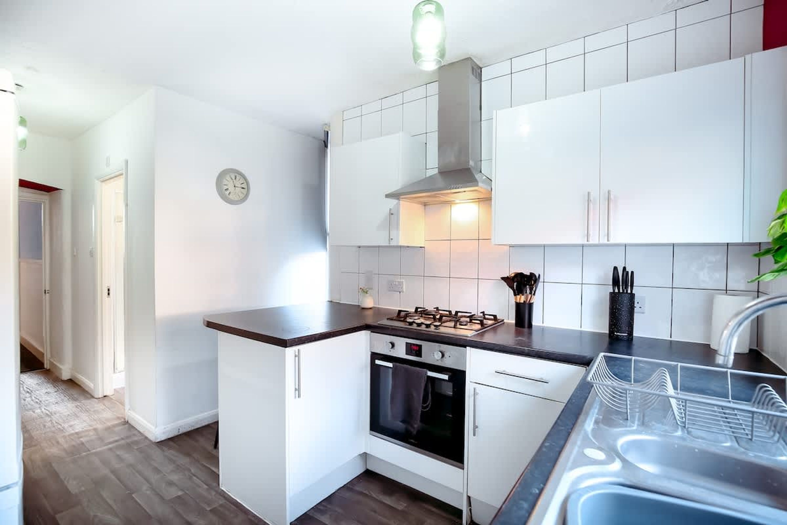 A compact kitchen with white cabinets, a gas stove, an oven, and a stainless steel sink.
