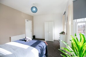 Ein Hotelzimmer mit Bett, Schrank, Heizkörper und einem großen Fenster.