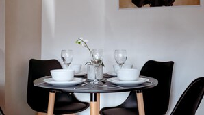 A dining table with white plates, bowls, and glasses, surrounded by black chairs. - Perfect Booking 4 Bed Home in Leytonstone (London)