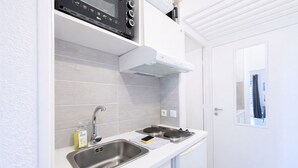 Une cuisine compacte dotée d’un évier en acier inoxydable, d’un four encastré et d’un four à micro-ondes.