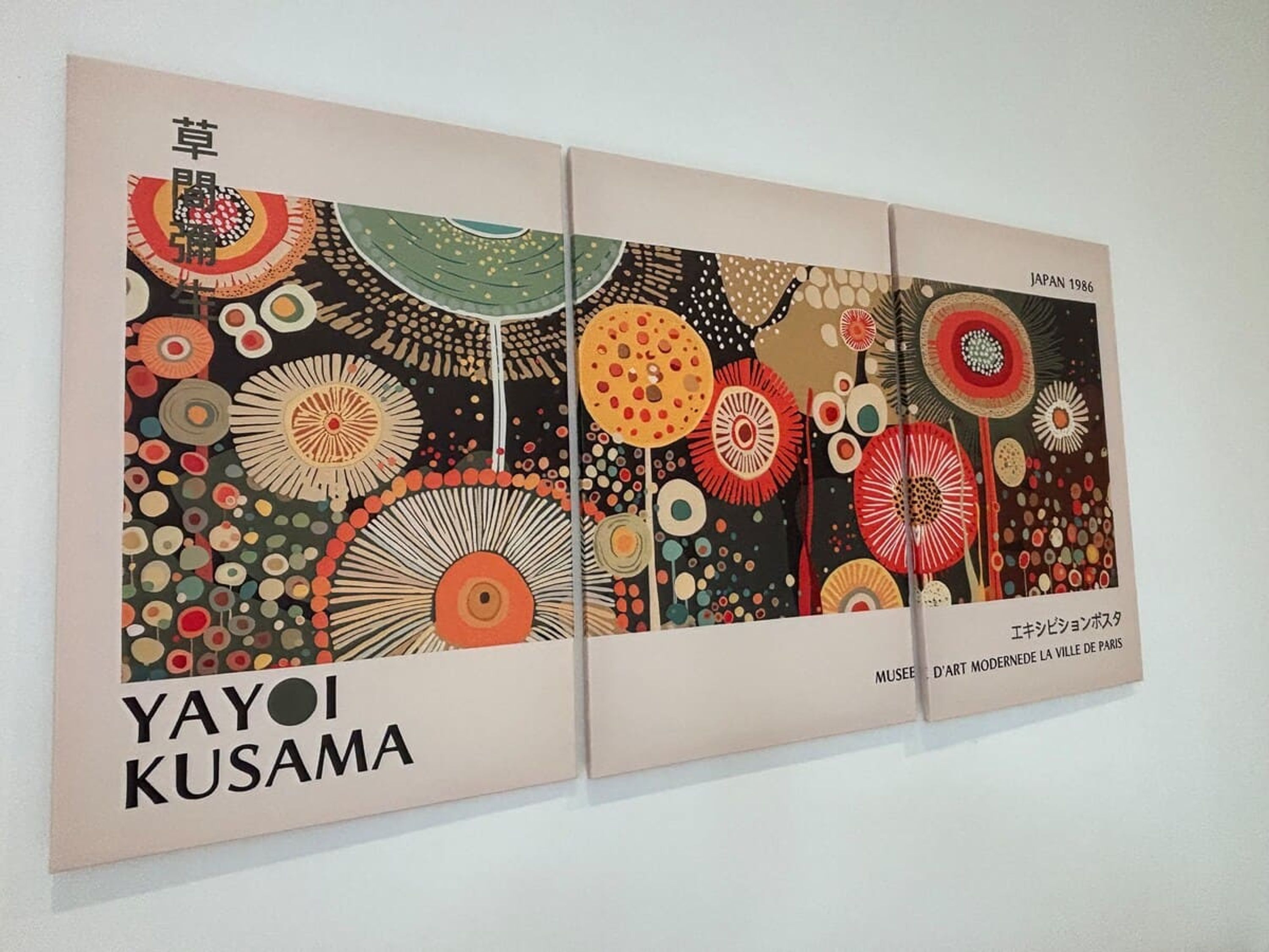 Ett inramat konstverk med titeln ”YAYOI KUSAMA” som föreställer abstrakta blommönster och innehåller japansk text.